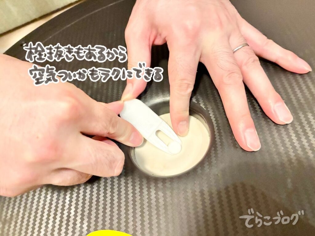 バランスドームの空気栓を専用器具で外す様子